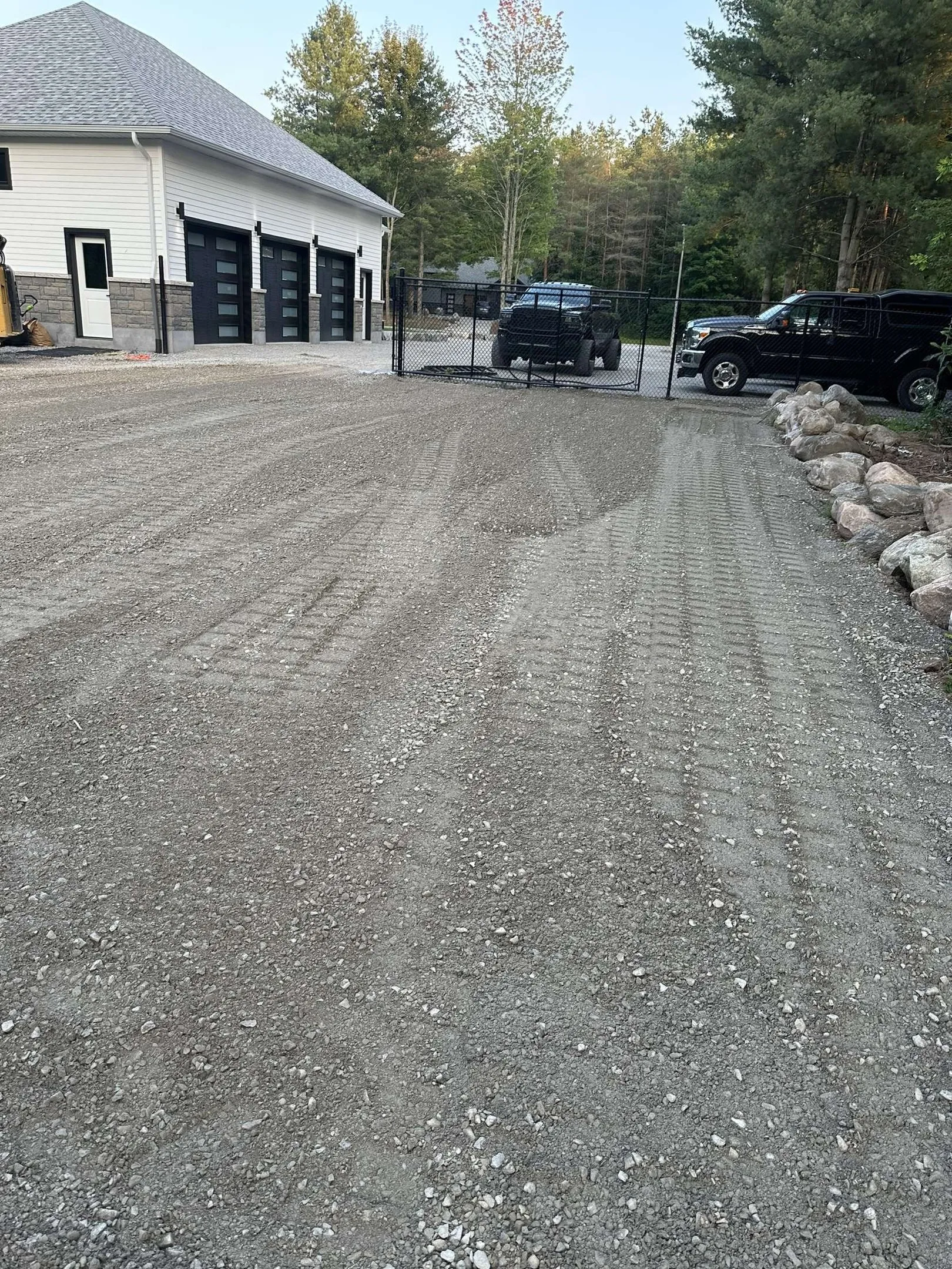 Freshly graded driveway beside a garage