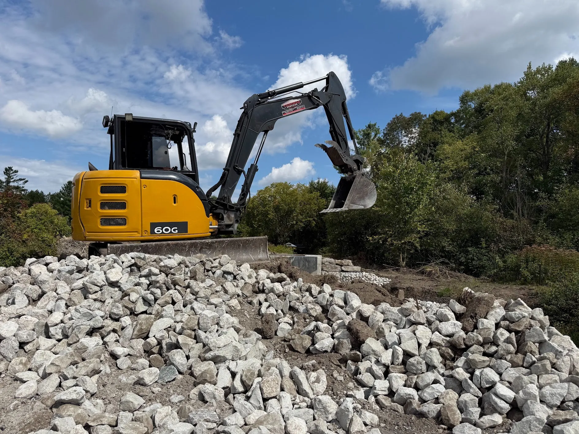 Mini excavator working beside a pile of rock