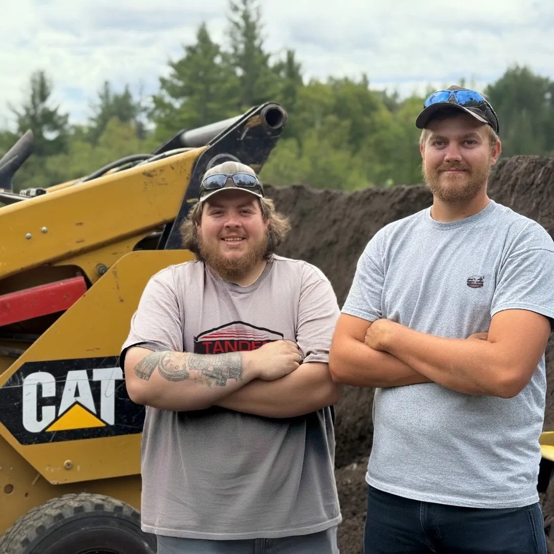 Duston and Gavin standing in front of Tandem Services equipment