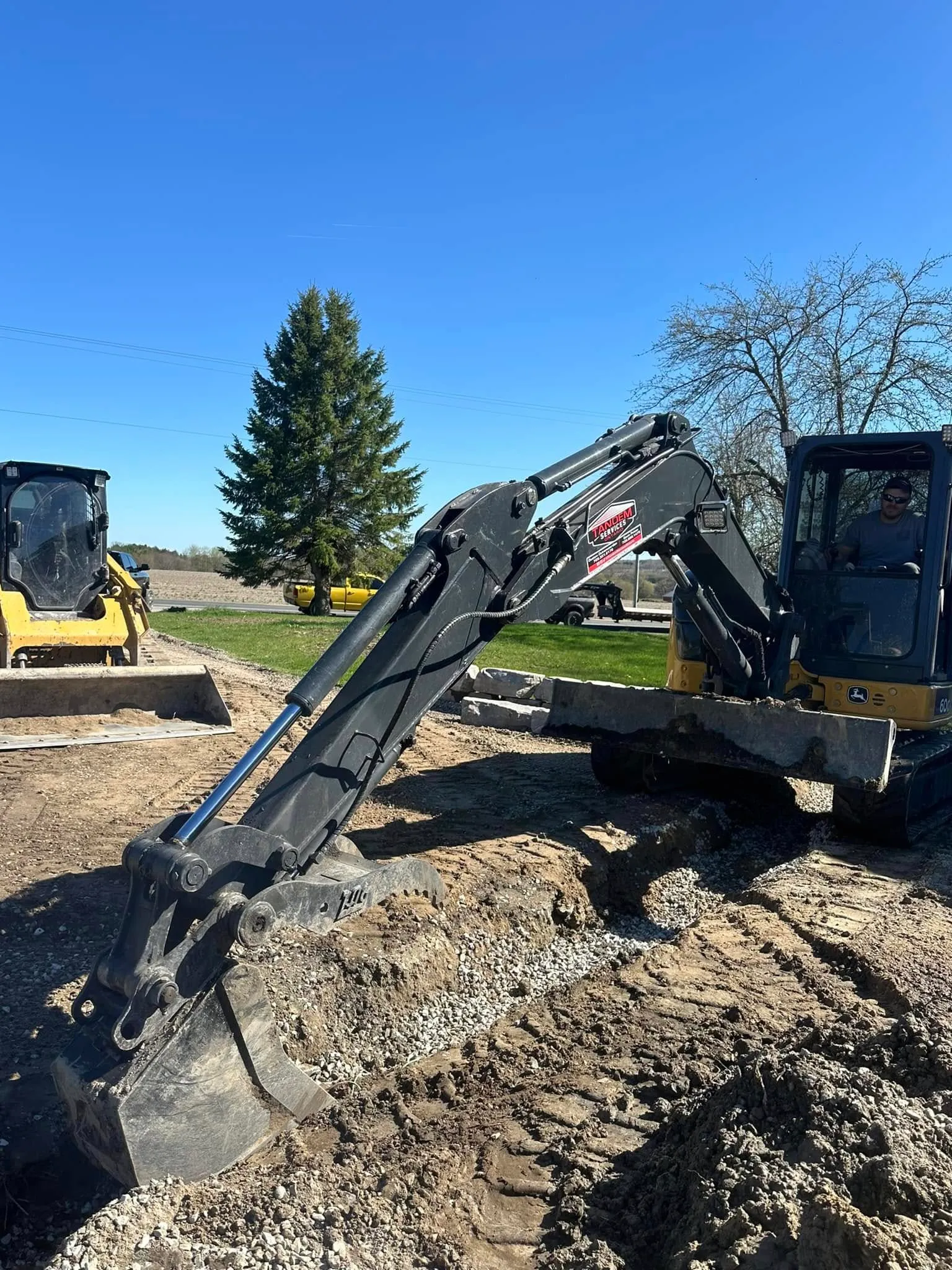 Tandem Services mini excavator digging beside a property